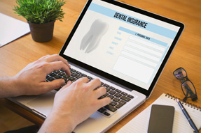 Patient filling out dental insurance form on laptop