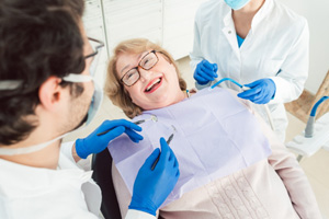 Woman with glasses smiling at dentist in treatment chair