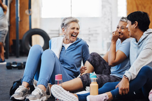 Group of woman smiling while sitting on floor in gym