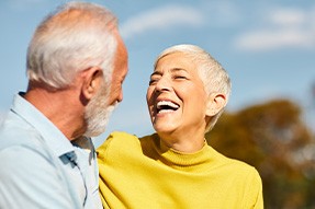 Woman in yellow shirt smiling at man in blue shirt outside